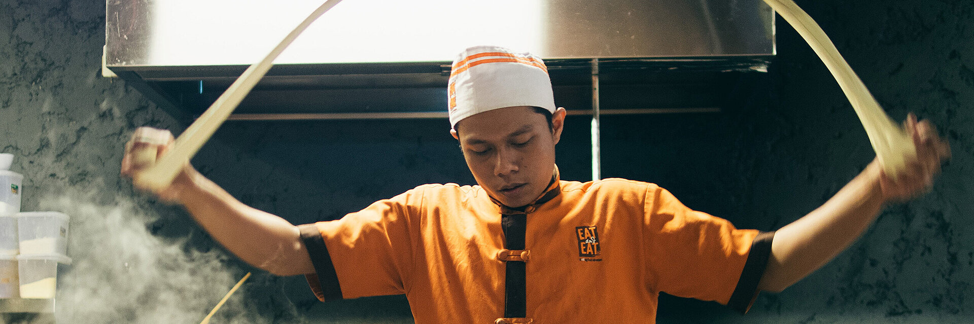 [Translate to Englisch IND:] Asian cook with embroidered working shirt