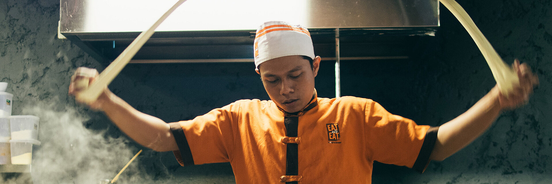 [Translate to Türkisch:] Asian cook with embroidered working shirt