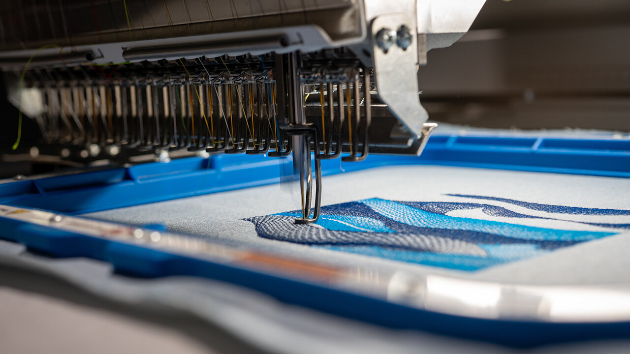 Embroidery machine stitching an abstract wave design using sustainable Polyocean thread
