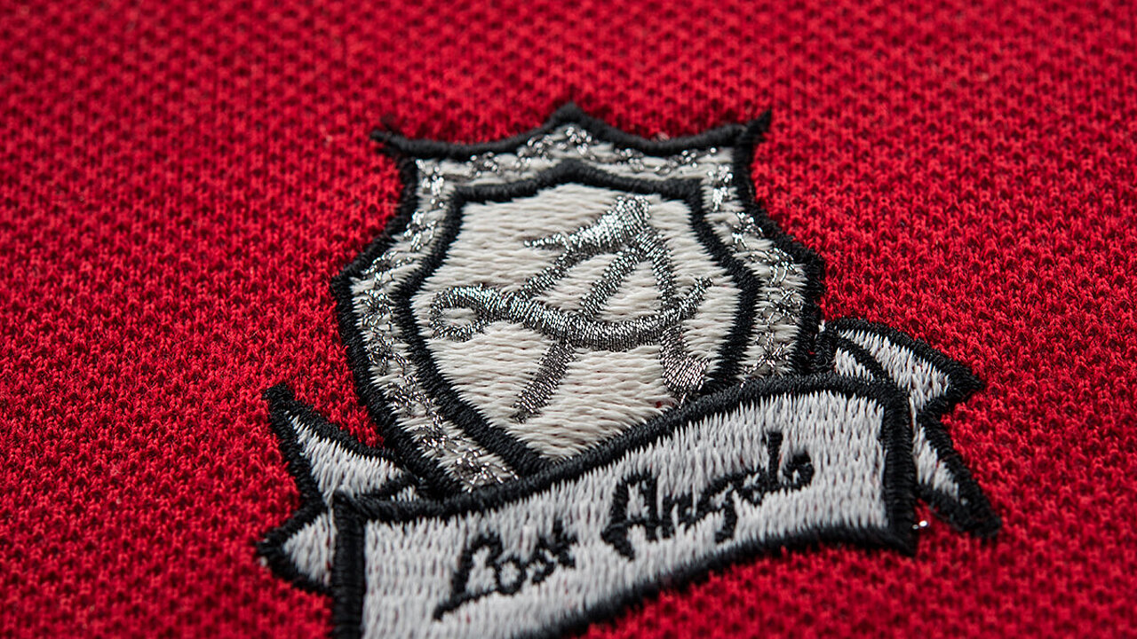 [Translate to Thailändisch:] grey patch "lost angels" embroidered on red promowear fabric