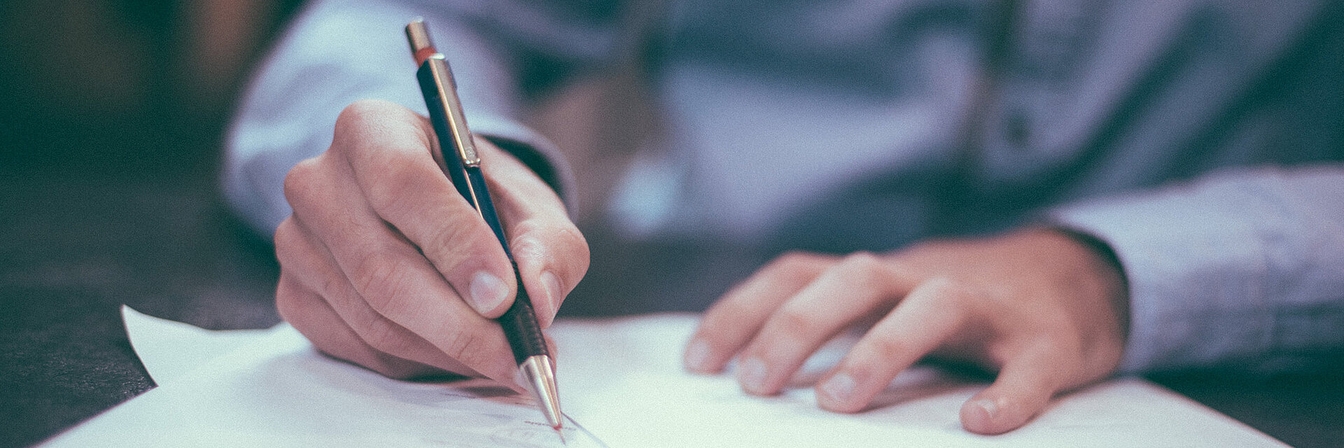 [Translate to Italienisch:] Businessman writing on a paper