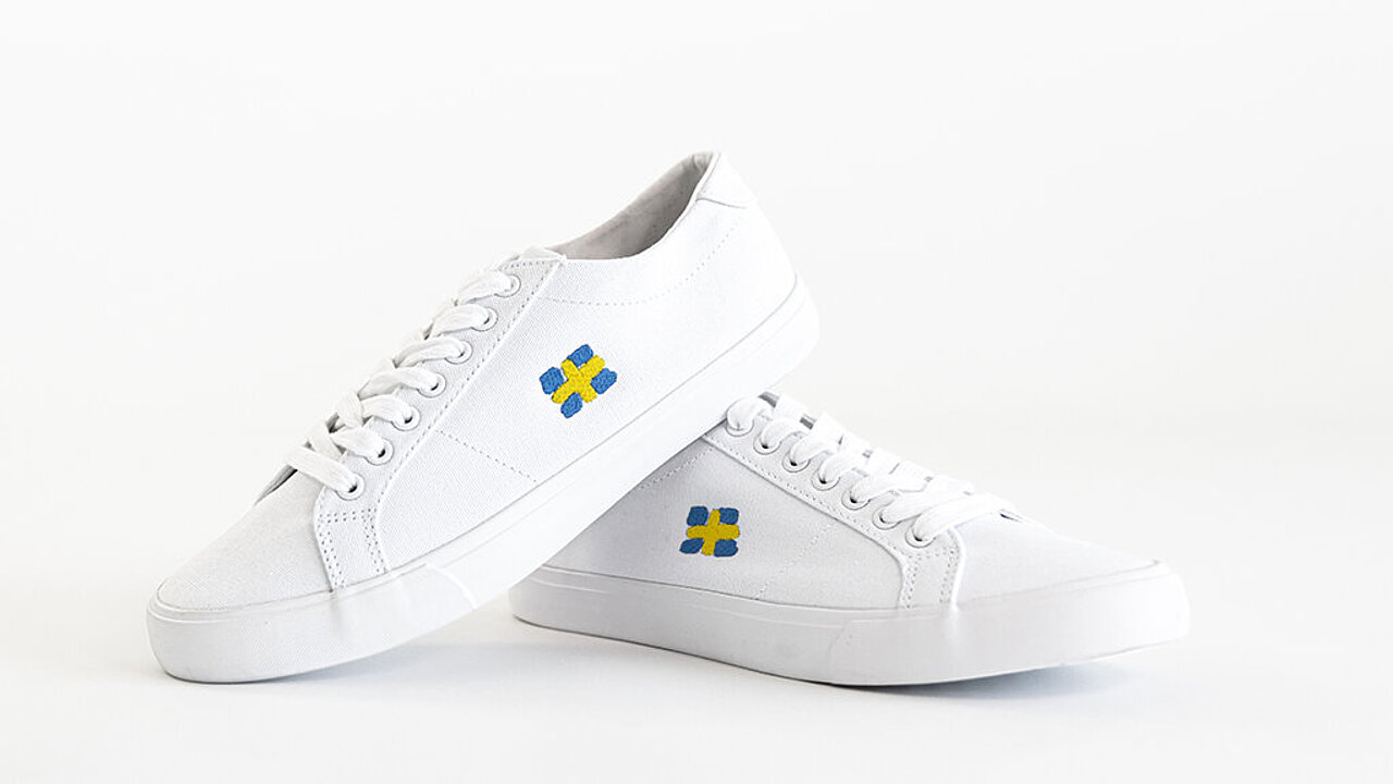 [Translate to Italienisch:] Shoes embroidered with Swedish flag design made wit Madeira Coloreel embroidery yarn 
