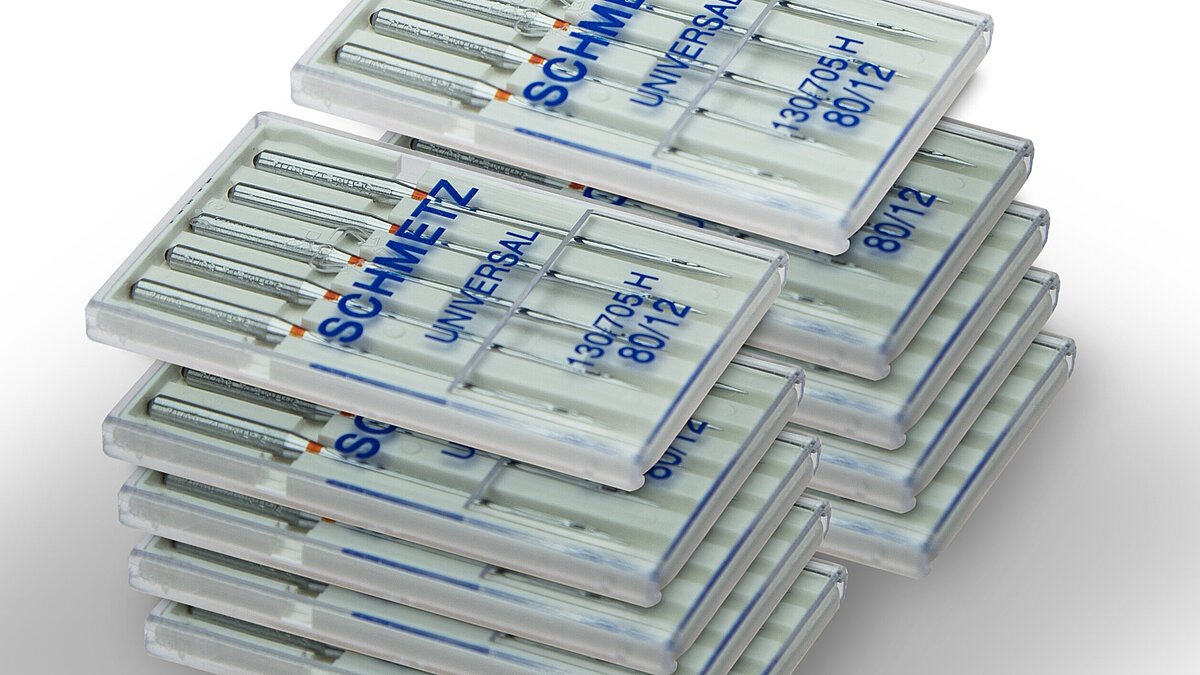 several 5 piece boxes of Schmetz Brother PR embroidery needles piled up