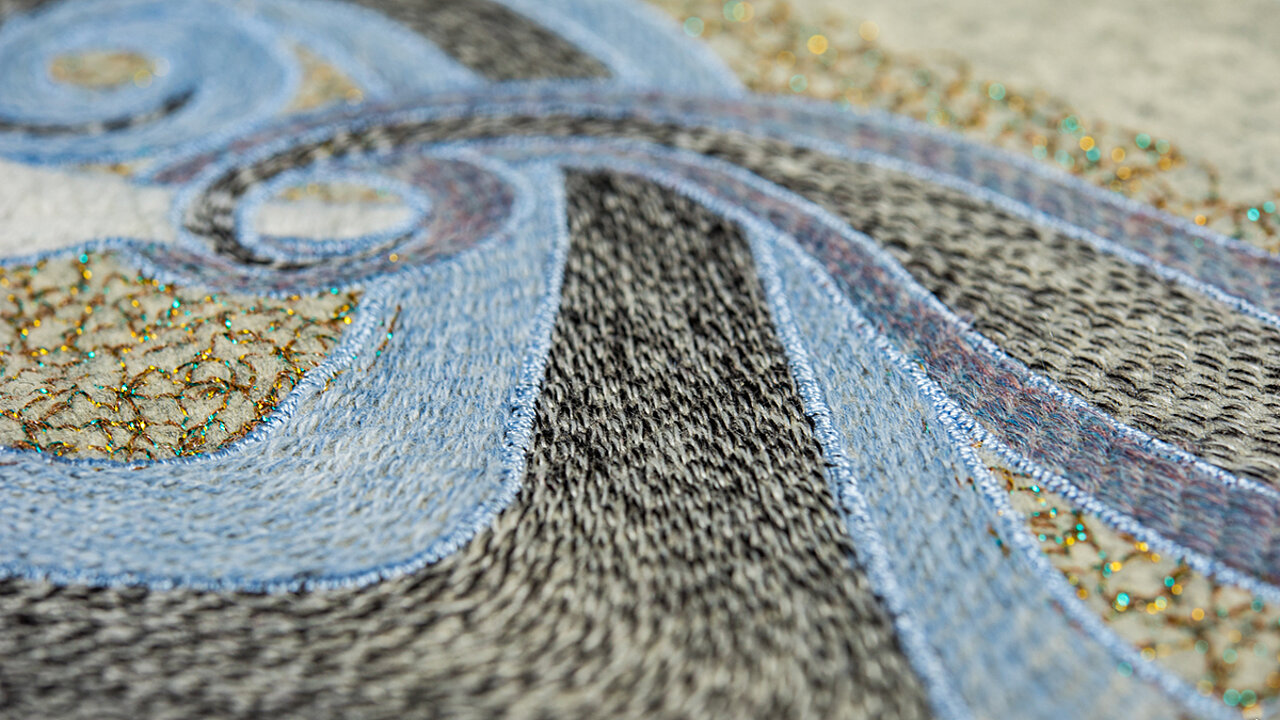 Close up of embroidery in blue, brown and yellow colors