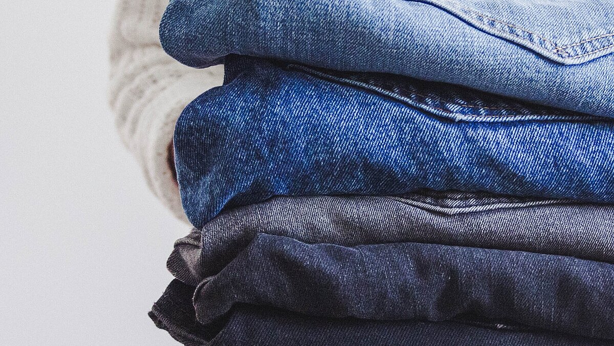 A stack of jeans trousers in different shades of blue