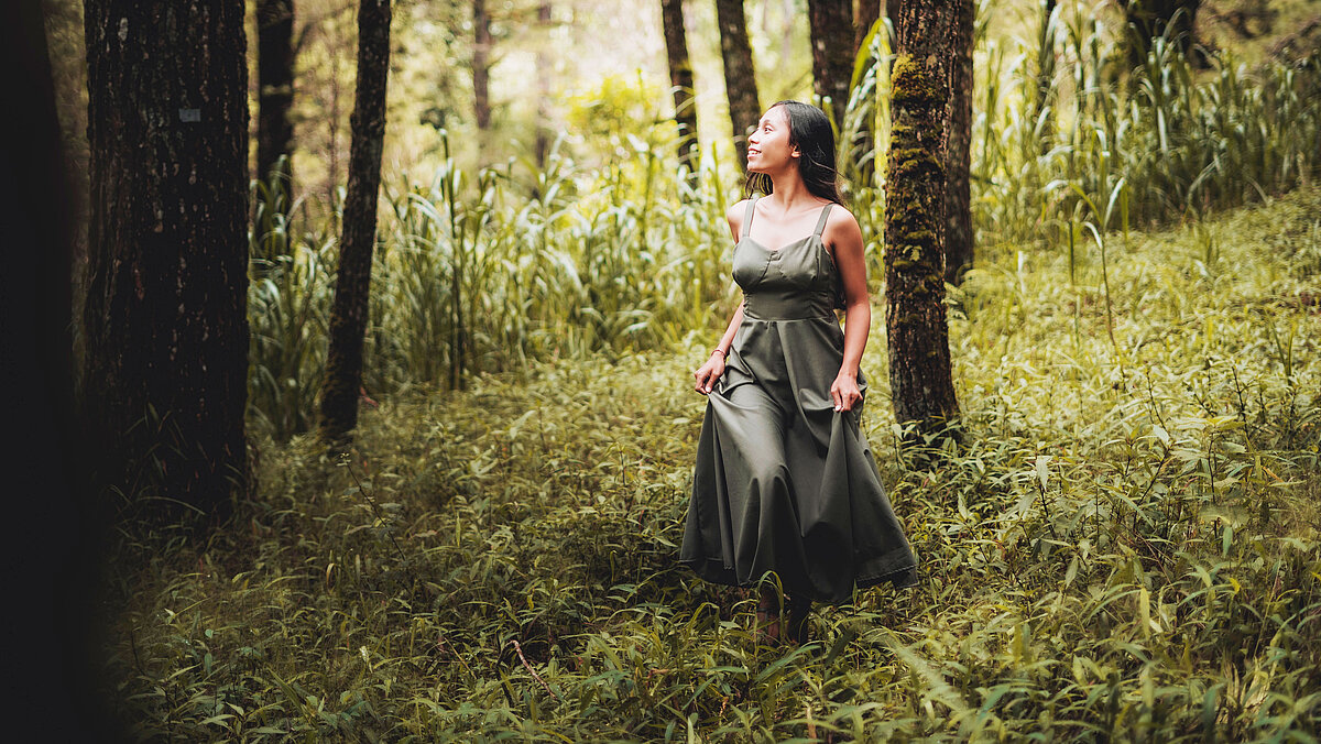 Woman with a green dress admiring the forest