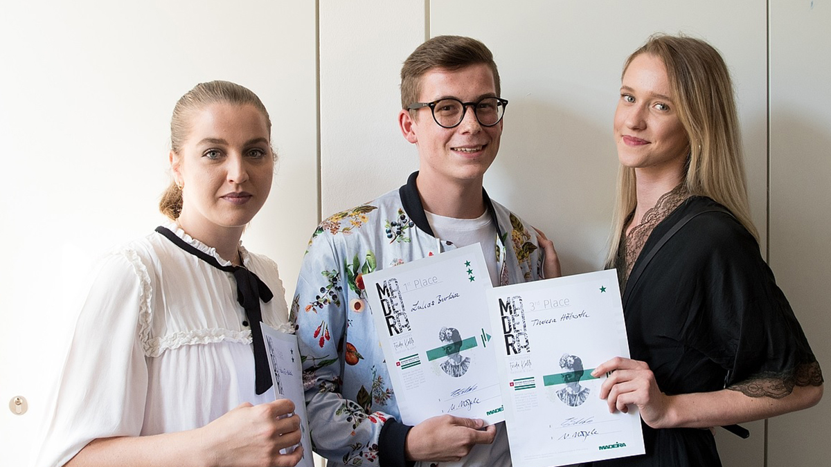 La photo gagnante montre les trois gagnants du concours. Ils brandissent leur diplôme avec satisfaction.